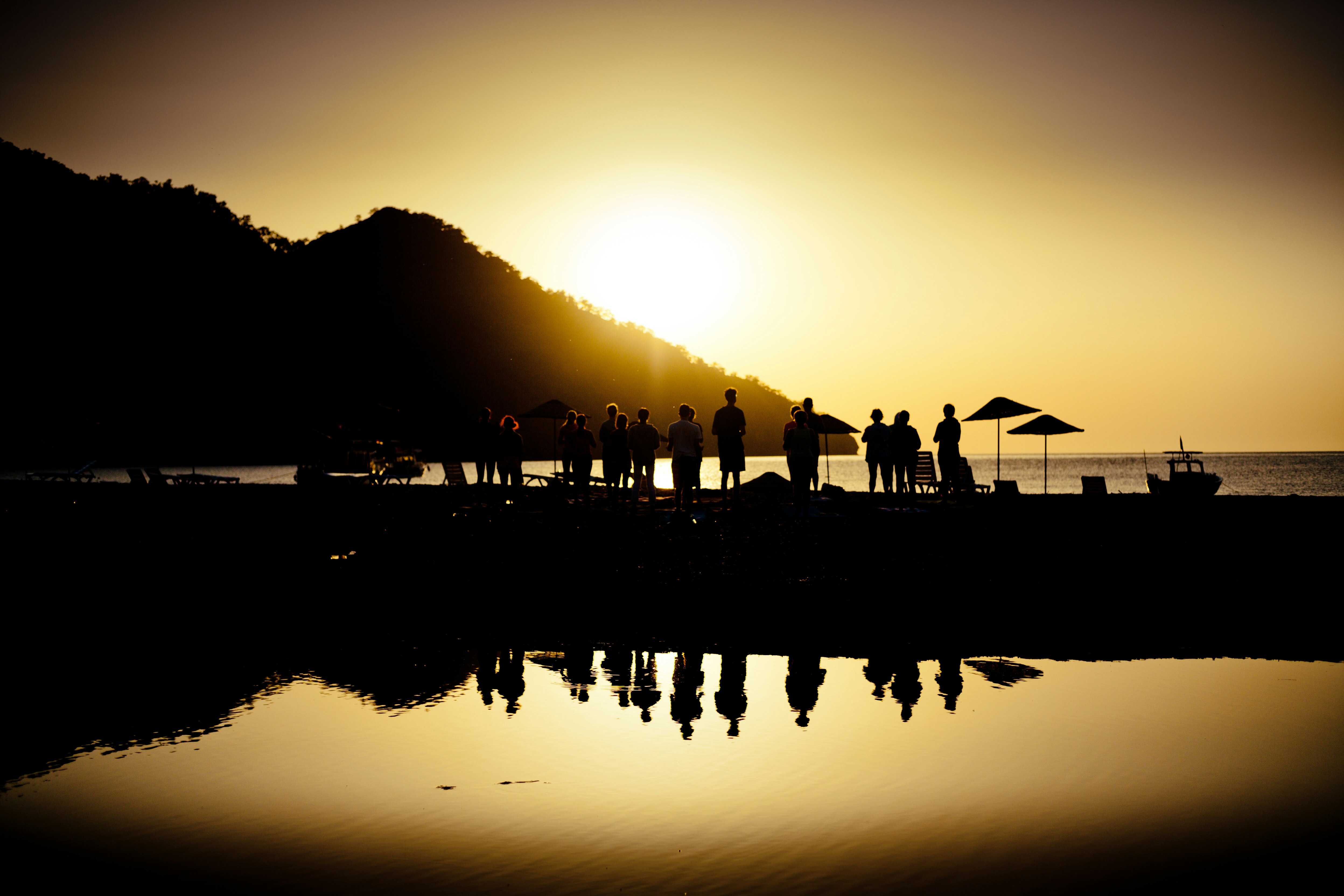 silhouette of people standing on dock during sunset